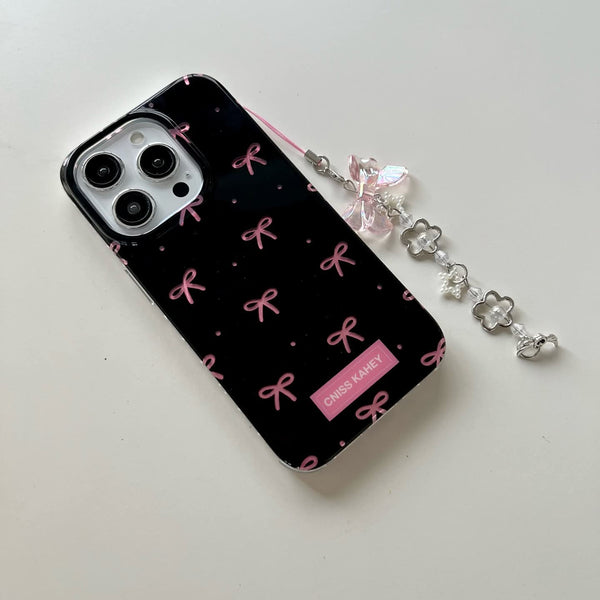 Elegant phone case features a glossy black finish with cute pink bow prints with charm